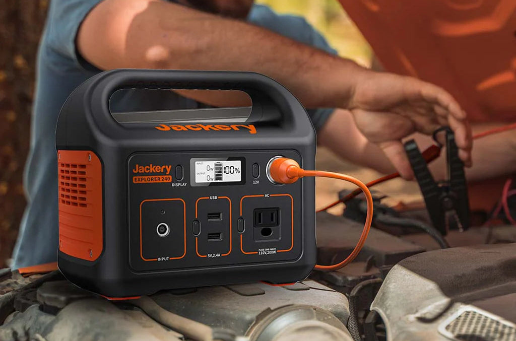 Jackery portable power station being used on a car hood with a person in the background.