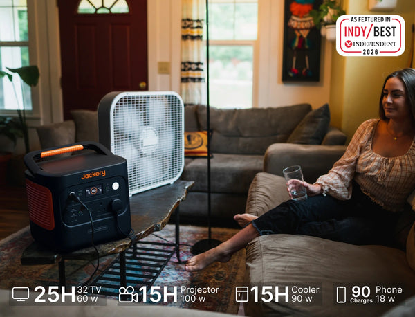 Woman staying cool at home during a UK heatwave with a fan powered by a Jackery portable power station.