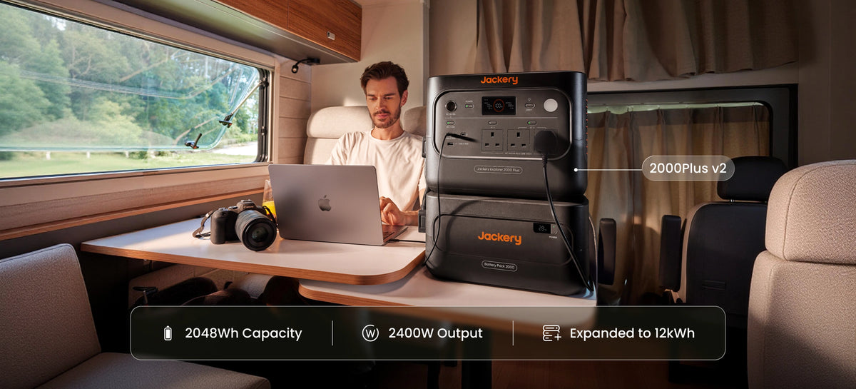 A man is sitting in the caravan, with a Jackery Explorer 1000 Plus V2 portable power station and a battery pack 2000, which are powering for his devices.